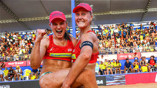 Cruz Brasher beach volleyball champions celebrating at a tournament with fans in the background.